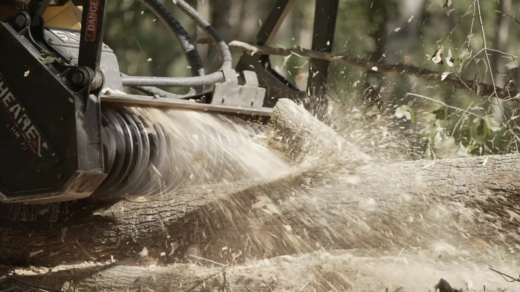 Mulching machine working a dense treeline with dust and mulch in the air