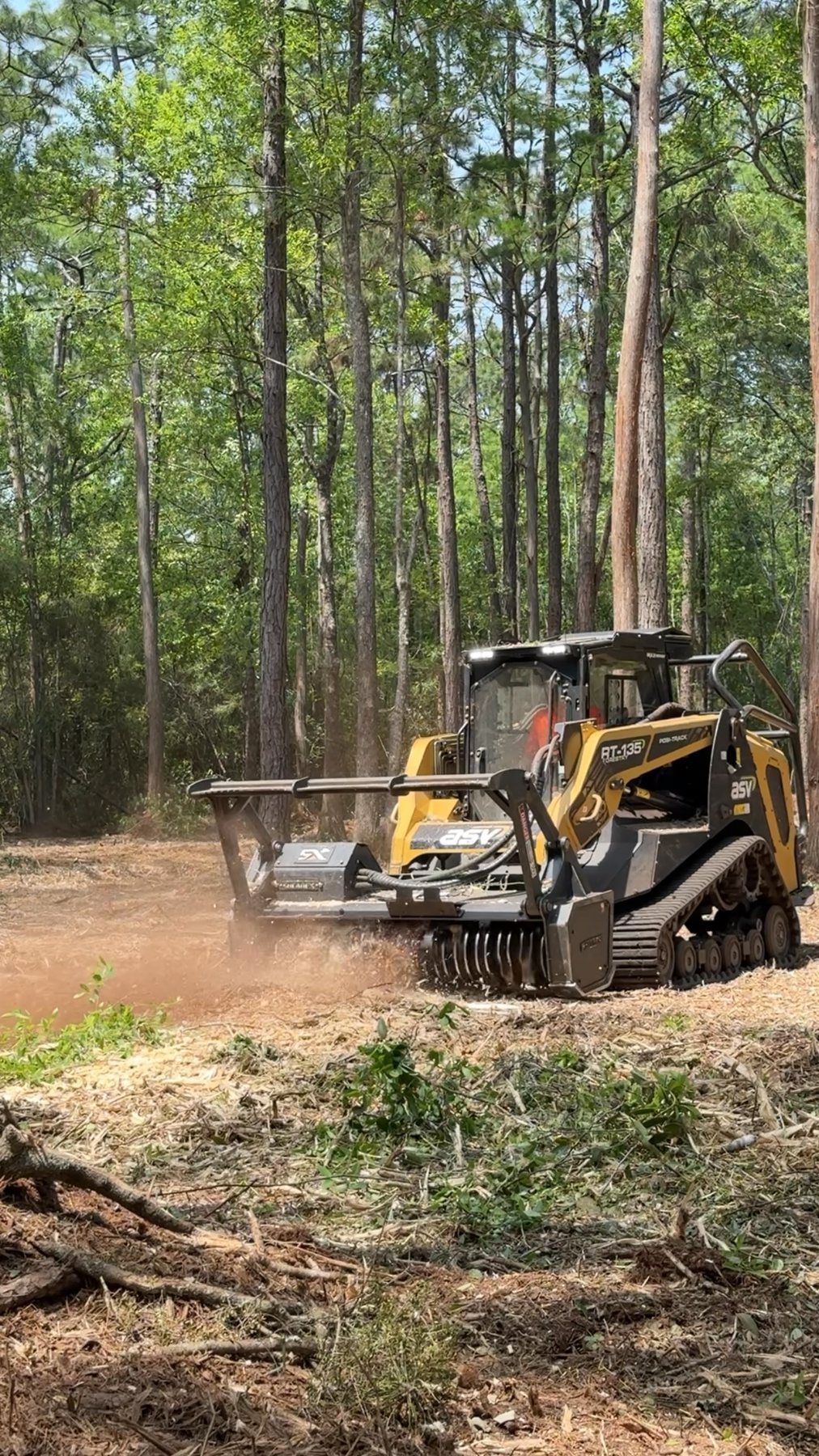 Forestry mulcher throwing a stream of wood chips while grinding underbrush