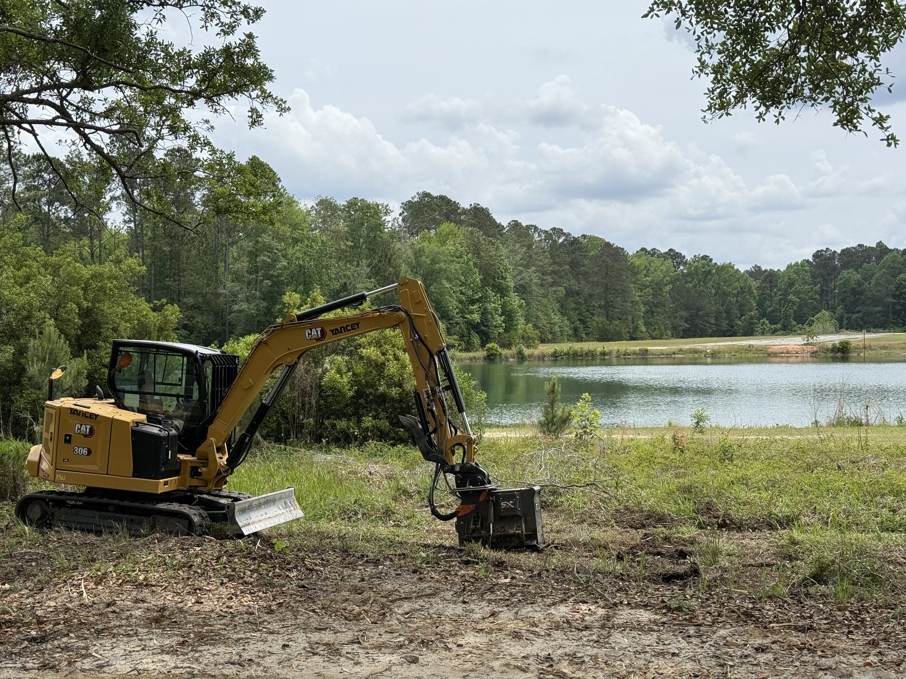 Reshaped pond bank cleared of scrub with an excavator working the edge